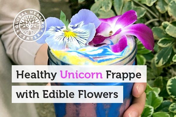 A glass cup of healthy unicorn frappe with edible flowers.